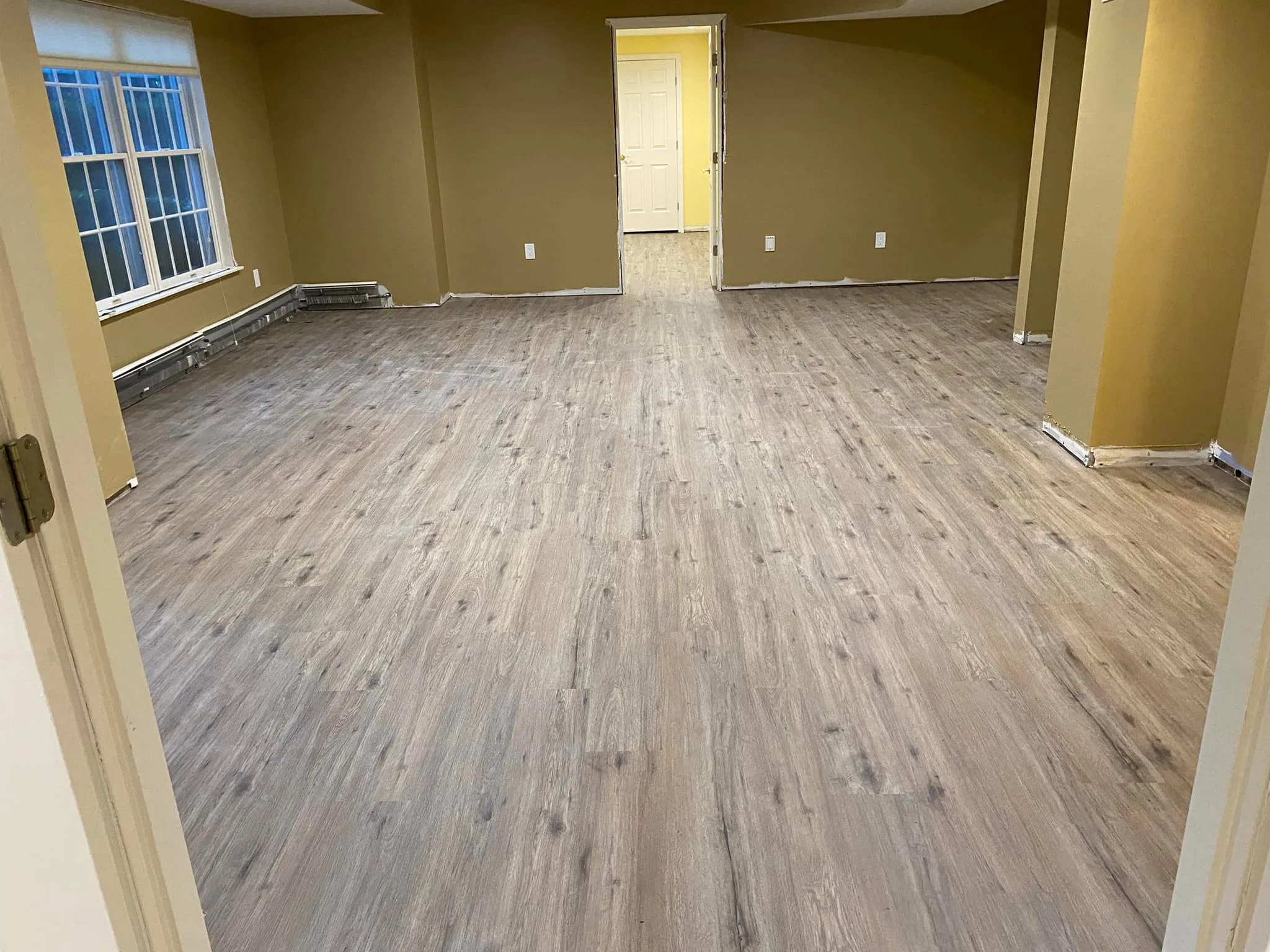 Comprehensive view from a doorway highlighting the uniform finish and layout of a professional basement flooring installation.